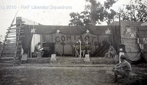 The Salbani Christmas Show 1942. A burnt-out basha used as stage, a harmonica group performing while Lofty Laughton sits at piano. Note mike stand, and the loudspeaker is a domestic radio set. Photos & Text Courtesy Of George Barker-Read.